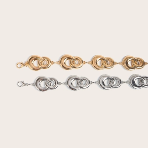 Close-up of interlocking gold and silver metal chain belts with secure lobster clasps