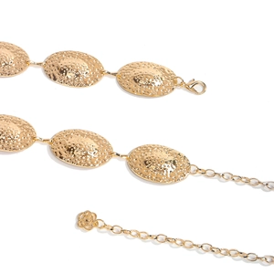 Detail view of gold hammered oval metal chain belt with lobster clasp and floral pendant