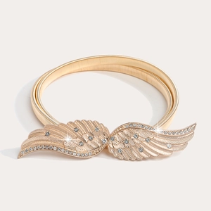 Detail of gold elastic spring belt featuring a crystal-studded angel wing buckle