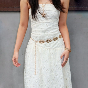 Detail of a hollow circular gold metal waist chain with starfish pendant on white dress