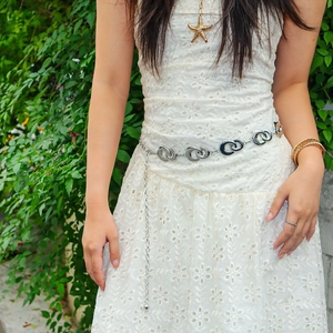 Elegant silver metal chain belt with hollow oval links on white lace dress