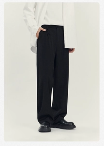 Dettaglio dei pantaloni neri da uomo con drappeggio elegante e design minimalista