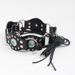 Détail d'une ceinture bohème en cuir noir avec clous turquoise et liens à glands