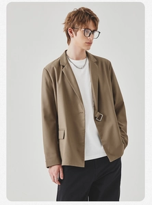 Detail of tan casual blazer featuring a unique side-buckle closure and notch lapels