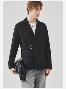 Detail of casual black blazer featuring unique side strap and silver metal buckle closure