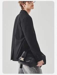 Detail of matte black leather shoulder bag with a large silver buckle and suit