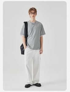 Casual herenoutfit met grijs T-shirt met witte contrastranden en een witte cargobroek in detail