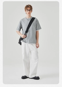 Detail van lichtgrijs nep-tweeluik T-shirt en witte cargobroek op model