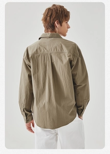 Back view of men's olive green loose-fit shirt showing the box pleat and fabric texture