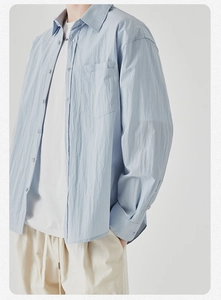 Close-up of light blue men's relaxed fit shirt with button chest pocket and textured fabric