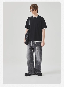 Detail van het gelaagde zwarte heren T-shirt met contrastzoom en grijze denim broek