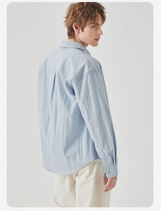 Detail view of the light blue long-sleeved shirt showing its texture and loose fit from behind