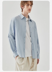 Detail of light blue long-sleeved shirt with classic collar and front chest pocket