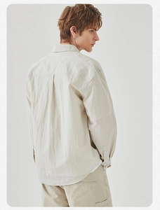 Detail view of men's loose long-sleeved shirt showing the back pleat and textured fabric