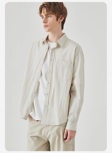 Detailed close-up of beige men's long-sleeve casual shirt with minimalist pocket and textured fabric