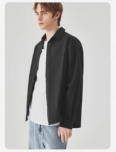 Detail view of a black long-sleeve men's shirt with chest pocket and classic lapel
