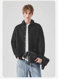 Detailed view of men's black long-sleeve shirt with casual leather bag and silver metal buckle