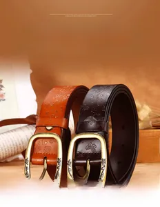 Close-up of embossed floral butterfly patterns on genuine leather belt with brass buckle