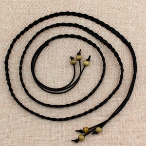 Vintage black braided belt for dresses with golden beads on a neutral background