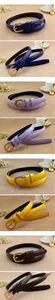 Détail de plusieurs ceintures en cuir verni aux couleurs vives avec boucles dorées et fini poli