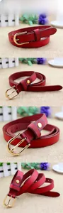 Close-up of red skinny leather belt with golden horseshoe buckle and cross-grain texture