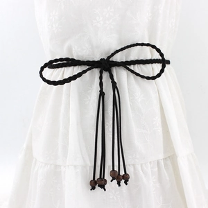 Handmade black woven belt with wooden beads tied in a bow over a white dress