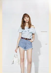 Detail of a brown leather belt with metal buckle styled with denim shorts and a blue top