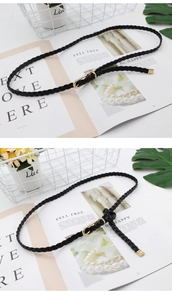 Detail of black woven PU leather thin belt with gold oval metal buckle and metal tip