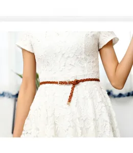 Close-up of brown braided PU belt with gold metal buckle on a floral lace dress