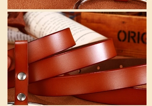 Détail d'une ceinture en cuir marron avec rivets argentés sur un fond en bois rustique