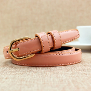 Ceinture fine en cuir verni rose corail brillant avec boucle dorée sur fond de lin beige