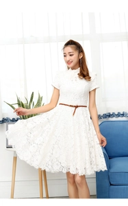 Detail of white lace dress featuring intricate crochet patterns and a brown skinny belt