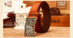 Close-up of vintage camel leather belt with floral embossing and bronze hollow buckle