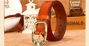 Detail of camel leather belt featuring floral embossing and vintage bronze floral buckle