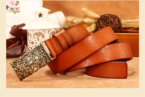 Close-up of vintage brown leather belt with floral embossing and bronze hollow buckle