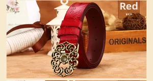 Détail d'une ceinture en cuir rouge à motif floral avec boucle en bronze et décor rétro