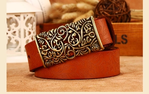 Close-up of brown leather belt with floral embossing and hollowed bronze buckle