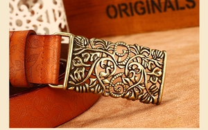 Close-up of vintage bronze buckle with hollow floral carvings on embossed leather belt