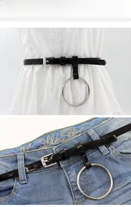 Détail de ceinture noire en similicuir avec anneau argenté sur robe blanche et jean bleu