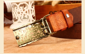 Detailed macro view of vintage brown leather belt with floral embossing and bronze hollow buckle