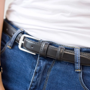 Ceinture classique en cuir noir avec boucle argentée à strass portée sur un jean bleu