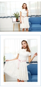 Détail d'une robe en dentelle blanche avec fine ceinture et col à ruban élégant