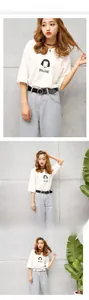 Close-up of a white graphic T-shirt with black circular buckle belt on light blue jeans