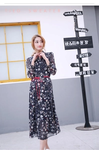 Détail d'une fine ceinture en cuir rouge avec anneau sur une robe longue à fleurs