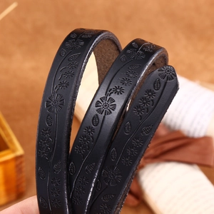 Slim black leather belt with embossed floral daisy pattern and vintage aesthetic