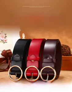 Close-up of three genuine leather belts with gold round buckles in black and wine red tones