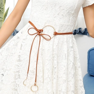 Fine ceinture en cuir marron avec boucle ronde dorée portée sur robe en dentelle