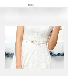Gros plan d'une fine ceinture blanche avec boucle ronde dorée sur une robe en dentelle
