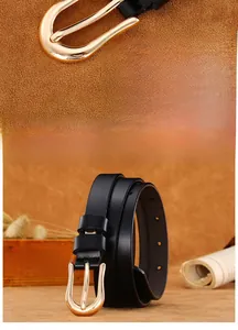 Detailed close-up of a slim black leather belt featuring a polished golden U-shaped buckle