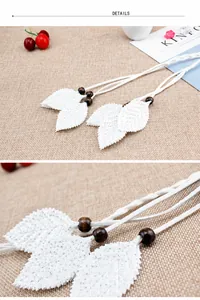 Close-up of white woven waist belt featuring sequined leaf charms and wooden beads details